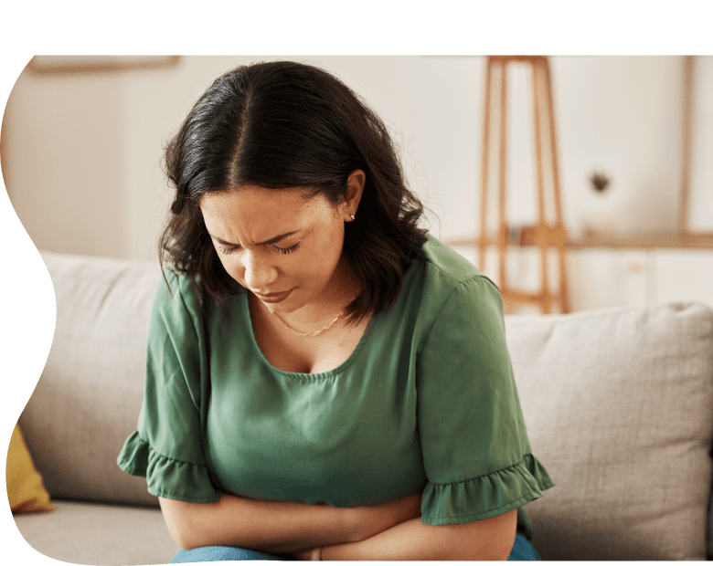 An image of a woman leaning over holding her stomach and frowning with her eyes closed.